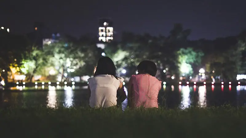 A girl and a boy communicating by the lake side at night time.