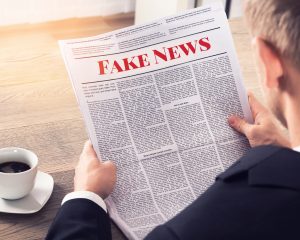 An overshoulder view of newspaper with Fake News written on it