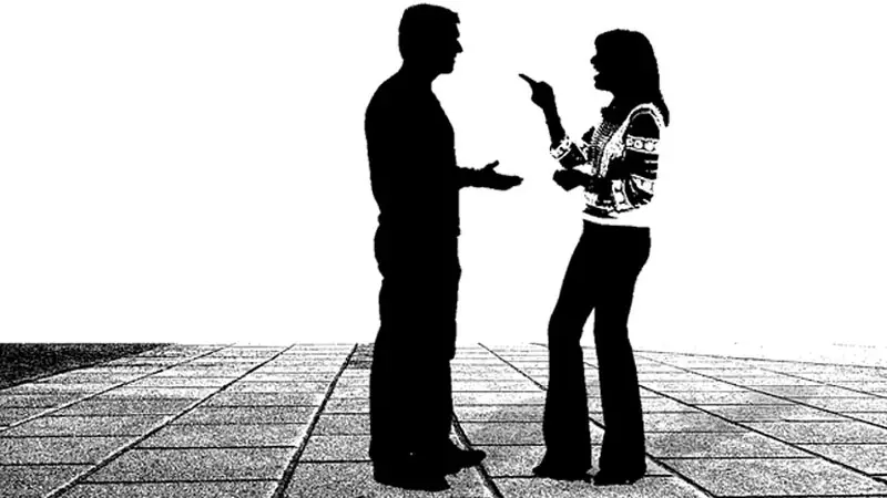 A woman laughing and pointing out her finger while talking to a man.