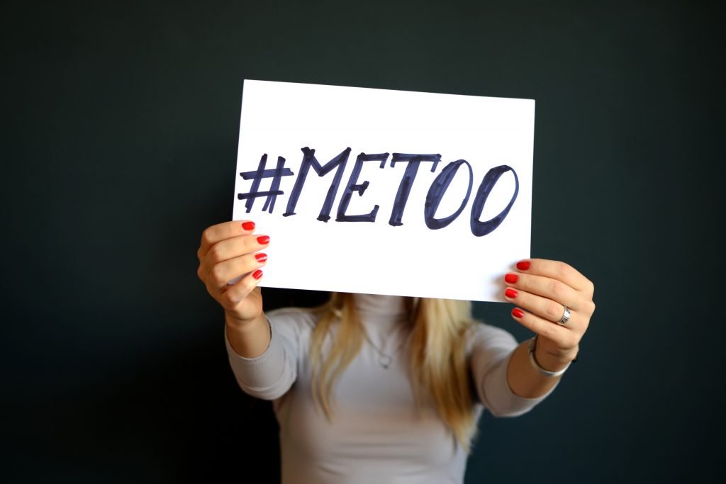 A woman holding a card that reads #metoo
