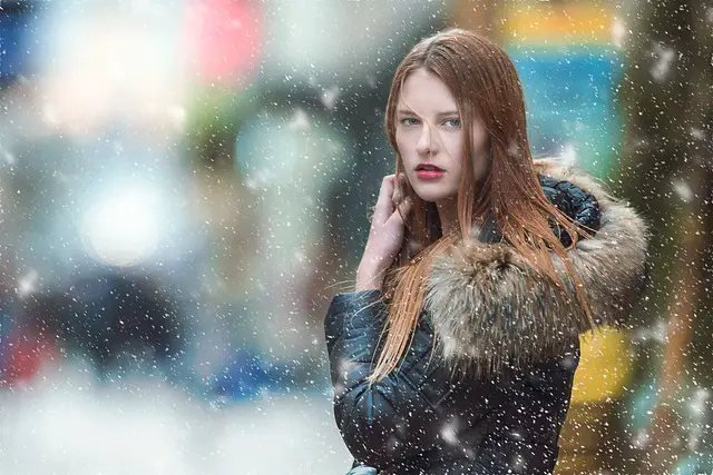 A woman wearing jacket and posing in a snowy weather.