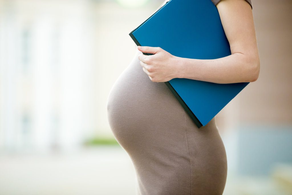 Close-up of belly of pregnant woman office worker